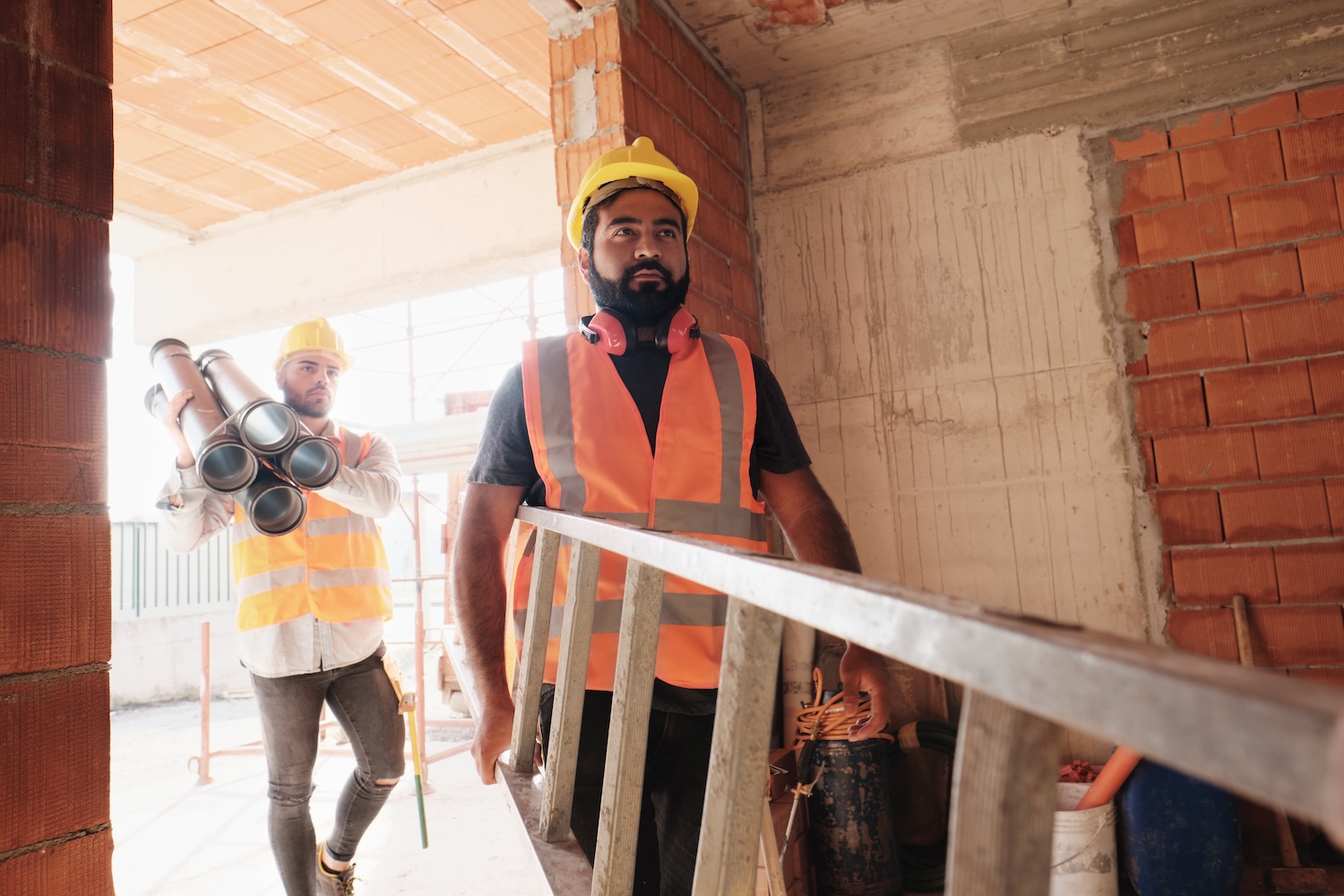 Carpentry service. Black handyman drilling wooden planks of table over light wall, free space. Furniture assembler man assembling desk and screwing details with electric drill
